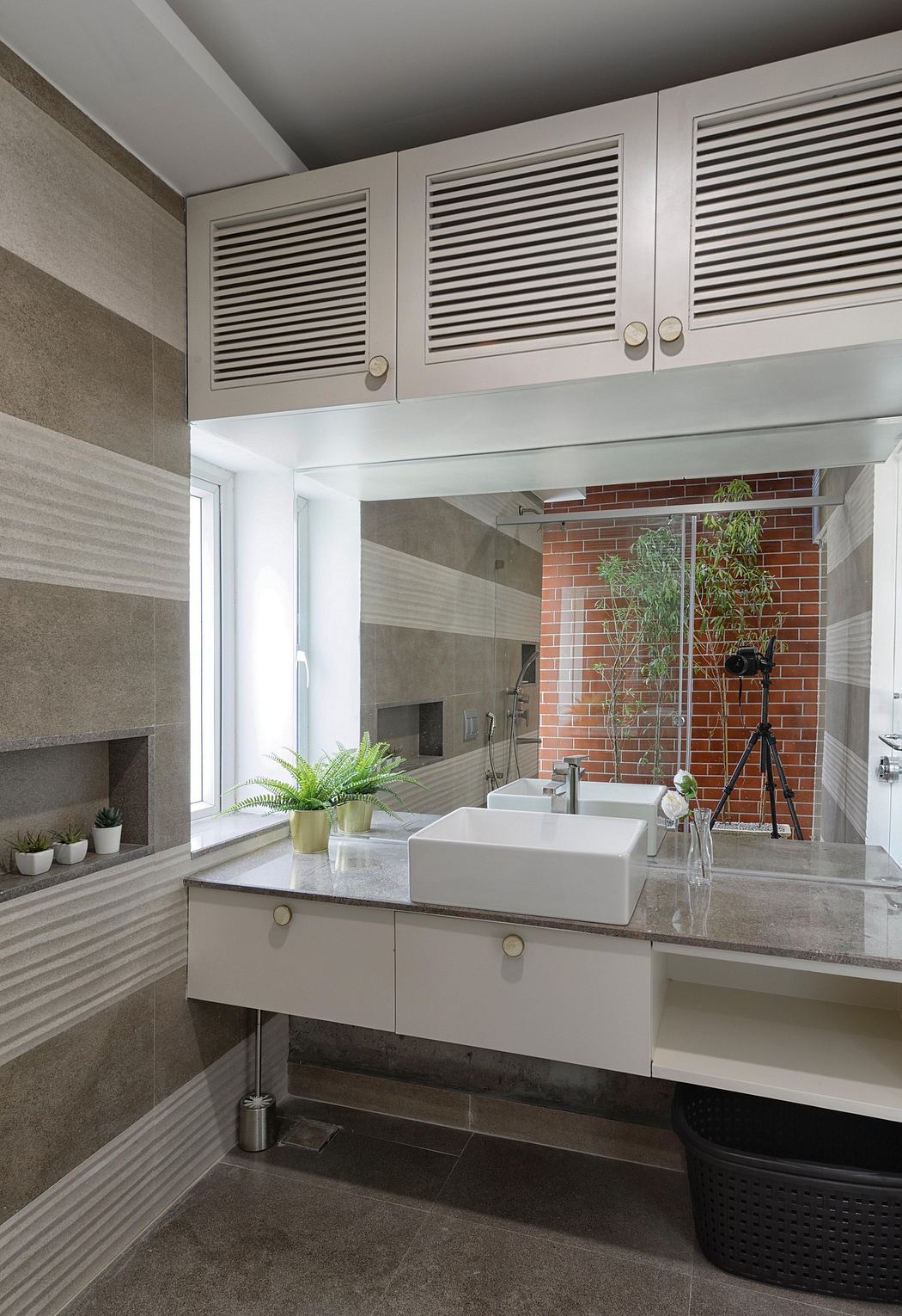 Sleek modern bathroom with concrete countertop, vessel sinks, and brick accent wall.
