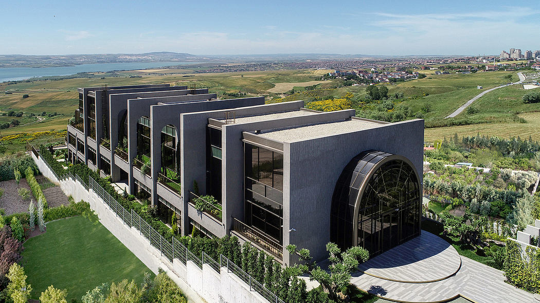 Dramatic architectural complex with curved and angular structures set against a scenic landscape.