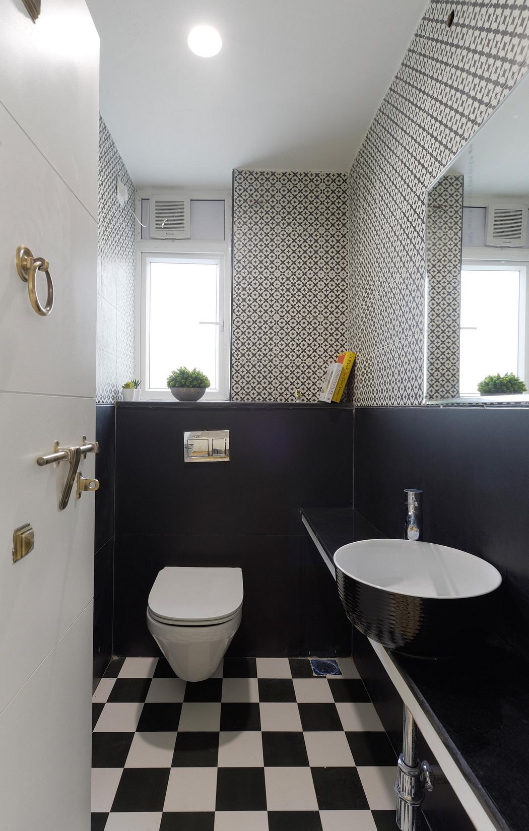A modern bathroom with black-and-white checkered floor tiles, a stylish vessel sink, and patterned wallpaper.