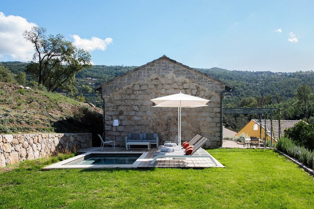 A beautiful stone farmhouse with a minimalist pool area and lush green surroundings.
