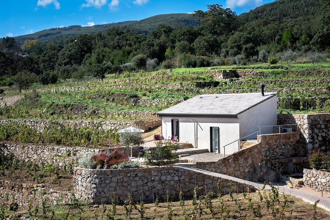 A cozy white cottage nestled among lush green hills, surrounded by stone walls and gardens.