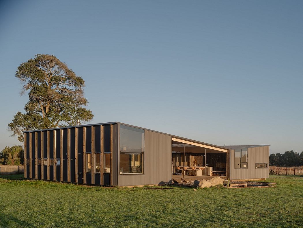 A modern, modular structure with wood and glass facade amidst a grassy field and trees.