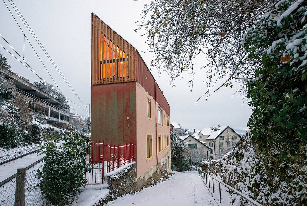 Vibrant orange-accented modern building with intriguing architectural elements in snowy setting.