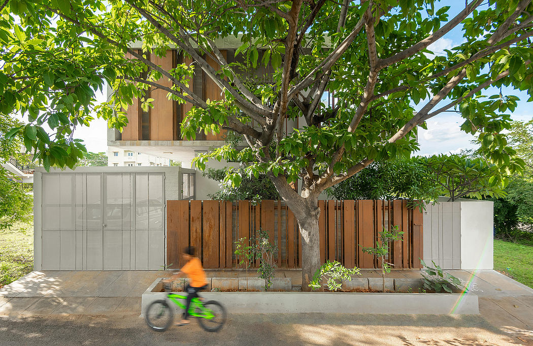 A modern, wood-and-glass residential building with a lush, leafy tree in the foreground.