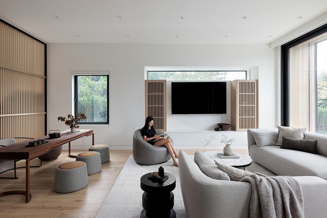 Minimalist living room with large windows, wood furnishings, and neutral seating.