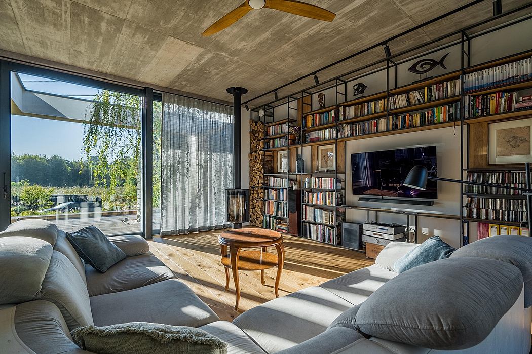 Rustic concrete ceiling, floor-to-ceiling bookshelves, cozy living room with large window.
