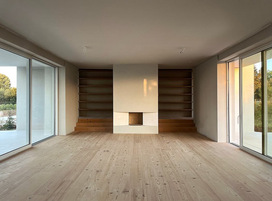 Spacious living room with wooden floors, shelves, and a large fireplace.