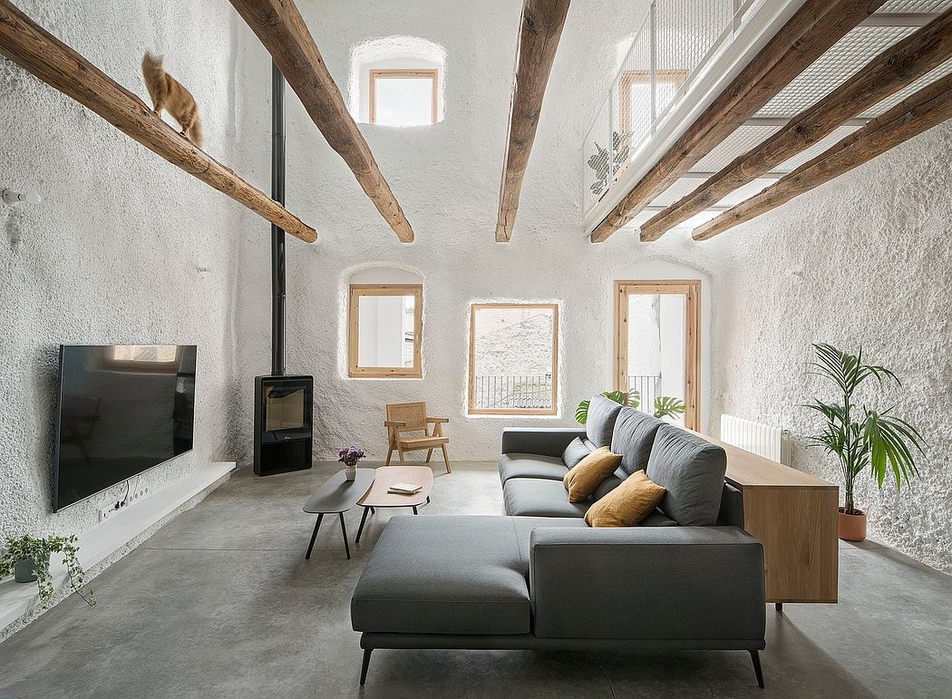 A spacious living room with exposed wooden beams, minimalist furniture, and large windows.