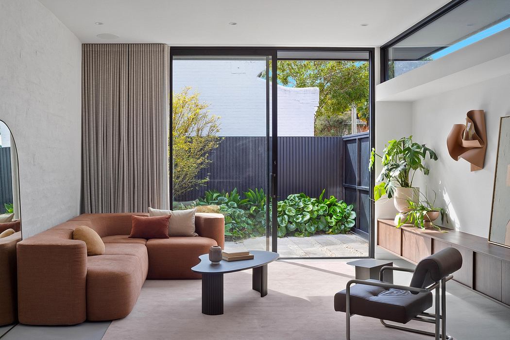 Cozy living room with large windows overlooking an outdoor garden and patio area.