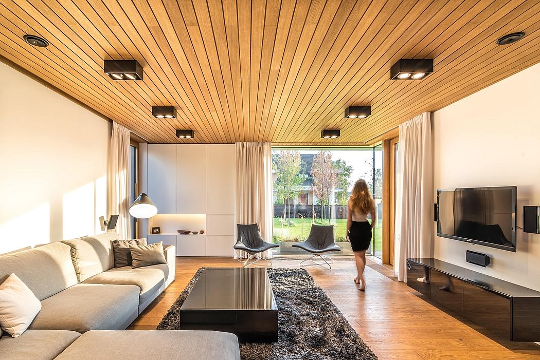 Elegant modern living room with wooden ceiling, minimalist furniture, and large windows.