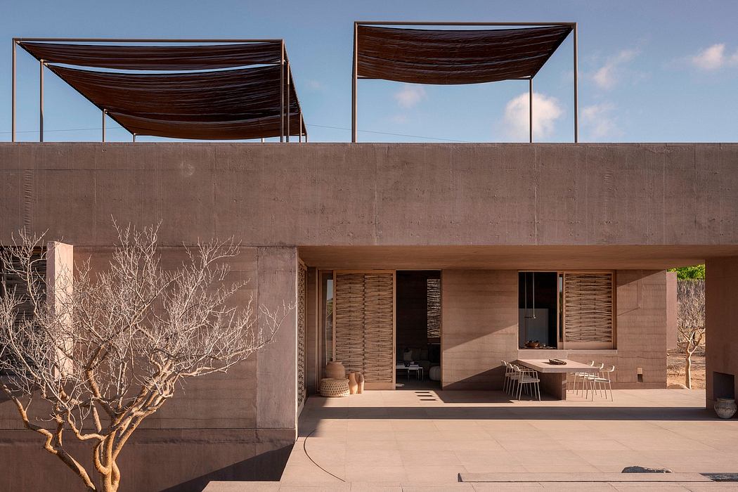 Modern desert house with distinctive cantilevered wooden roofs and woven screen walls.