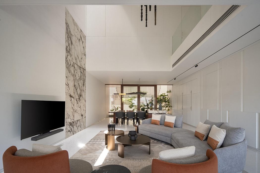 Spacious modern living room with minimalist furniture, marble wall accent, and abundant natural light.