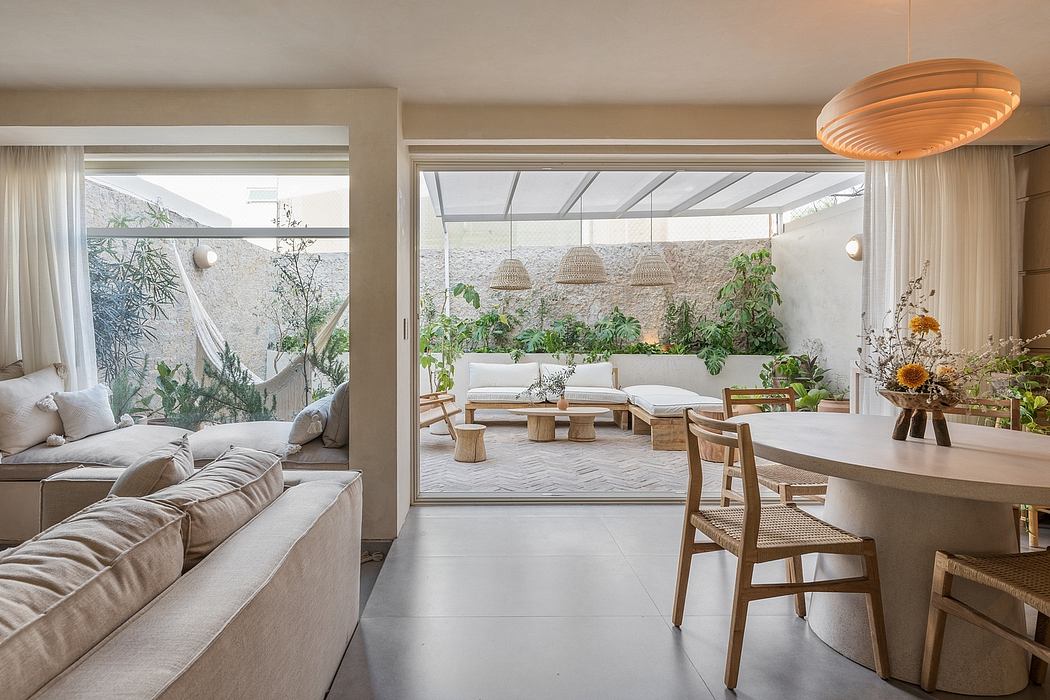 Spacious open-plan living with glass walls, plush seating, and lush greenery.