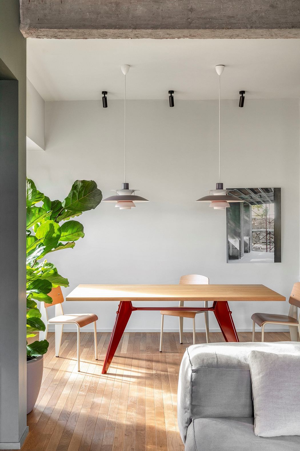 Minimalist interior with wooden dining table, modern pendant lights, and large potted plant.