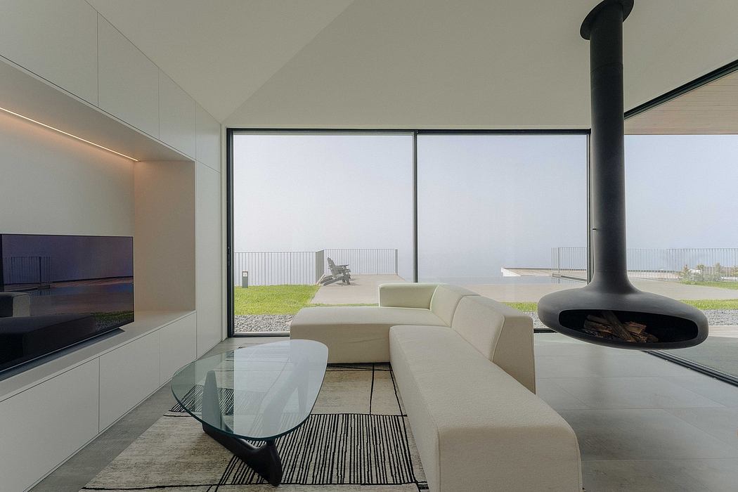 Minimalist living room with large windows, sleek white furniture, and a modern fireplace.