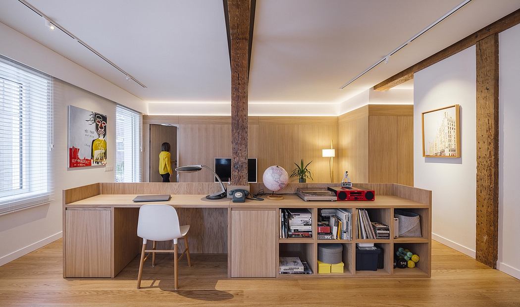 Spacious, modern home office with wooden built-in shelving, desk, and artwork.