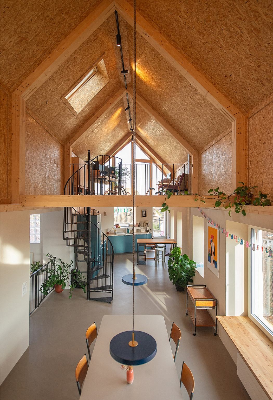 Charming open-concept space with vaulted wood ceiling, spiral staircase, and cozy decor.