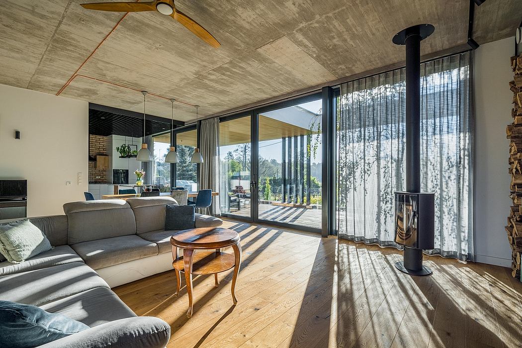 A modern, open-plan living space with concrete ceiling, large windows, and a cozy fireplace.