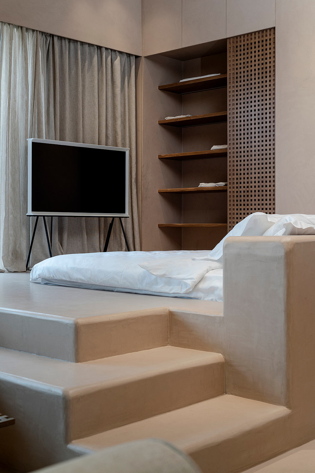 A modern bedroom with a TV, wooden shelves, and a minimalist, stepped platform bed design.