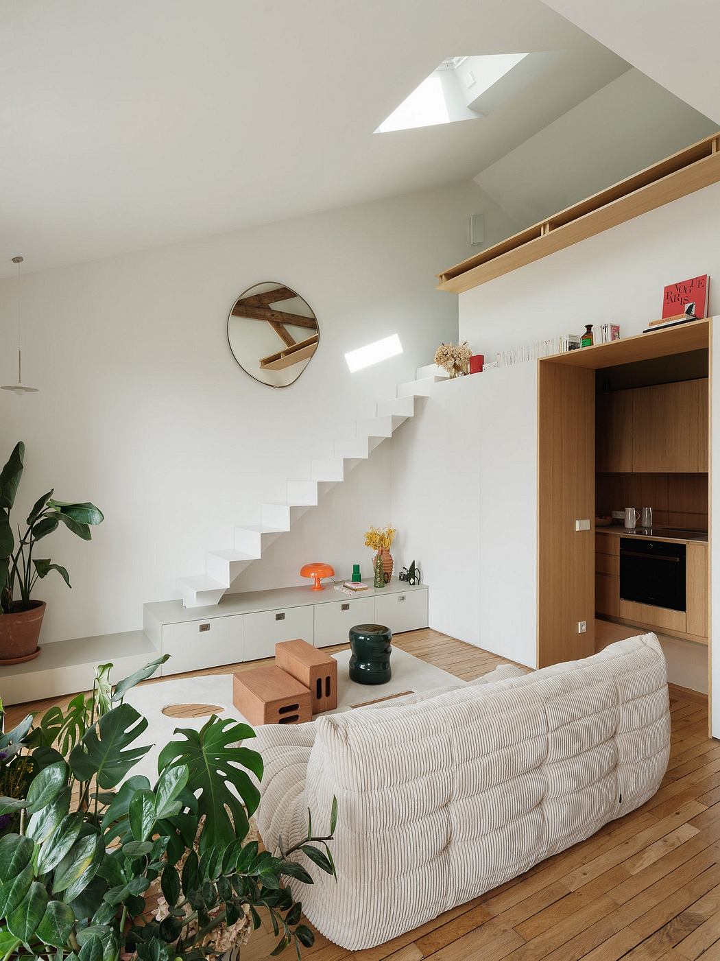 A modern, bright living space with white walls, wooden stairs, and a cozy sofa.