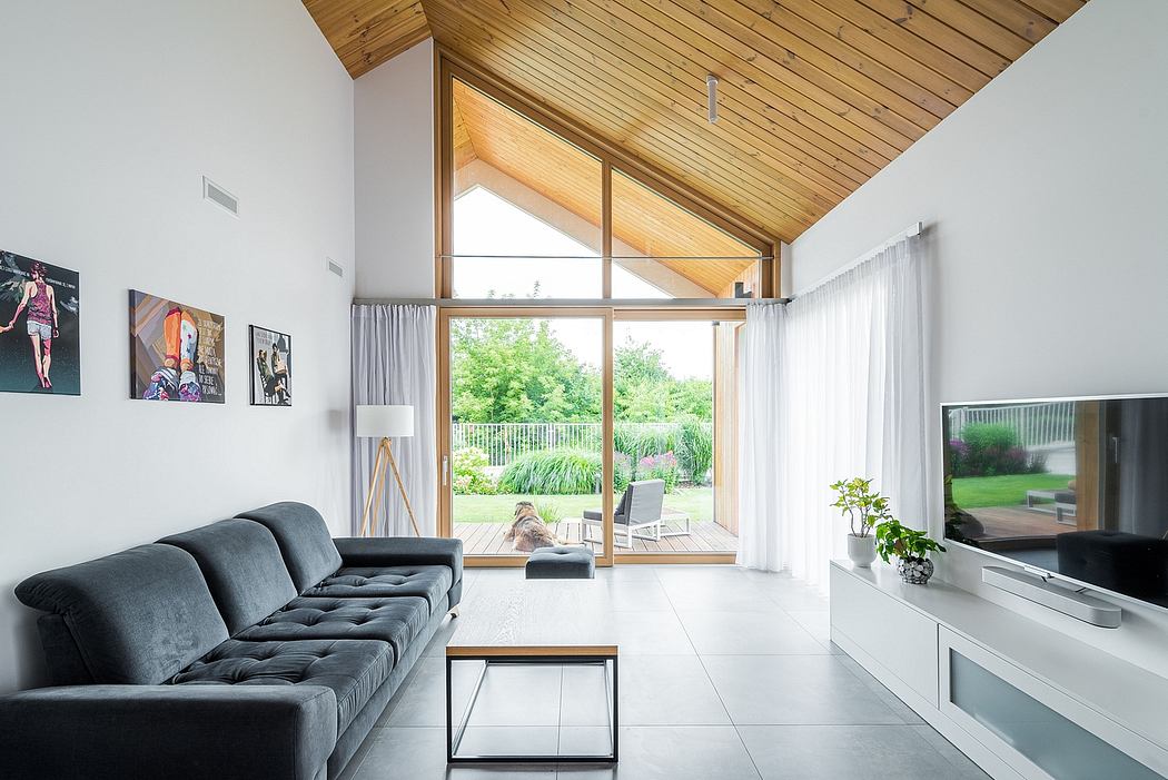 Spacious living room with high vaulted ceiling, large windows, and wood paneling.