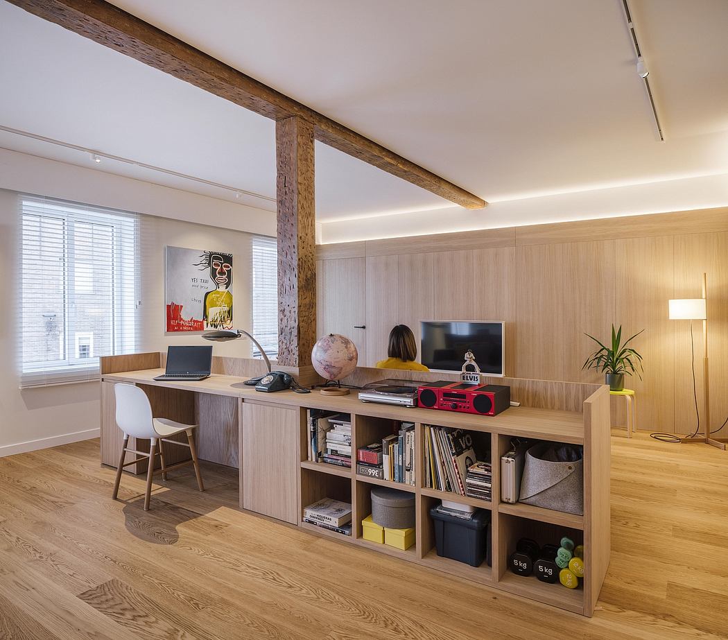 Warm-toned modern workspace with wooden beams, built-in shelving, and artwork.