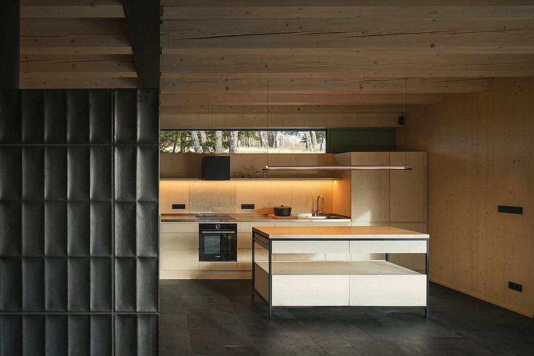 Modern kitchen with minimalist wood-paneled walls, sleek cabinetry, and large window offering forest views.