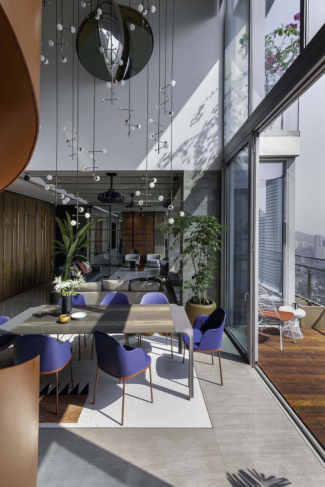 A sleek, modern interior with spherical light fixtures, plants, and a wooden dining table.