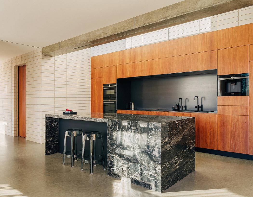 Sleek modern kitchen featuring warm wood cabinetry, black marble island, and integrated appliances.