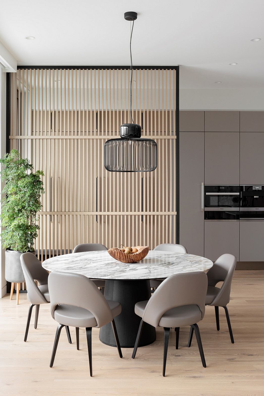 Sleek dining area with modern round table, upholstered chairs, and a stylish pendant lamp.