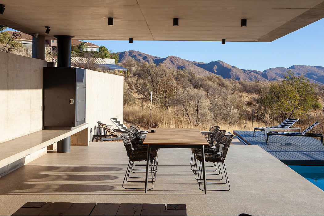 Outdoor patio with wooden dining table and chairs, surrounded by mountain views and a pool.