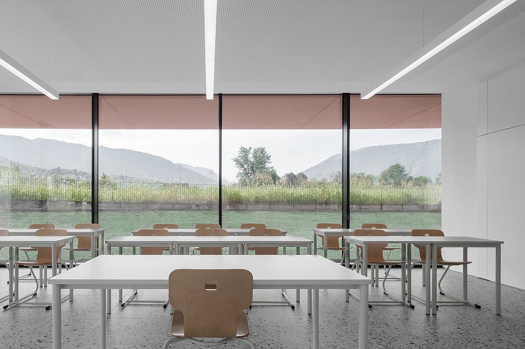 Modern classroom with minimalist furniture, large windows overlooking a lush landscape.