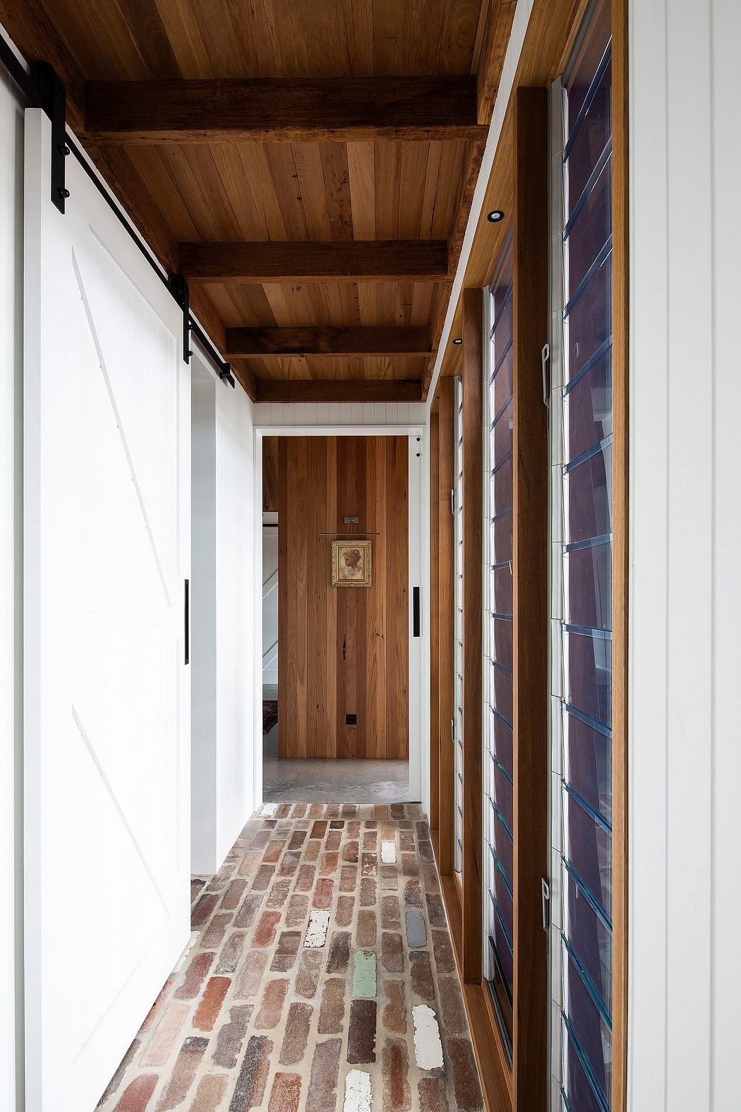 A cozy, rustic hallway with wood paneled ceilings, stone flooring, and a wooden door.
