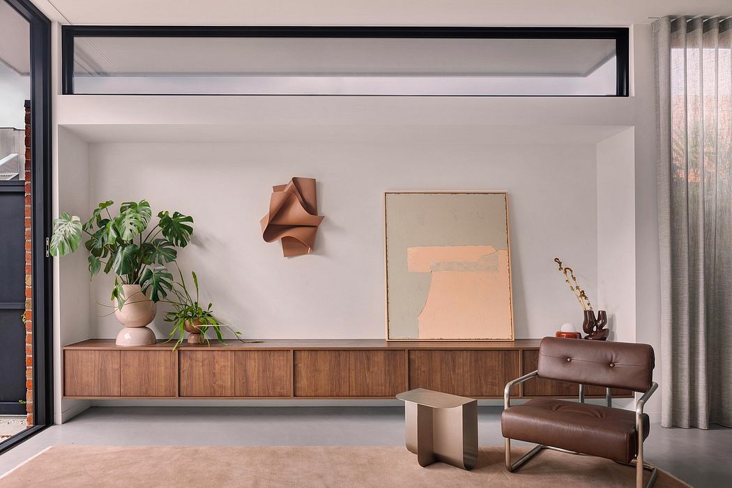 Minimalist living room with wooden console, potted plants, and abstract artwork.