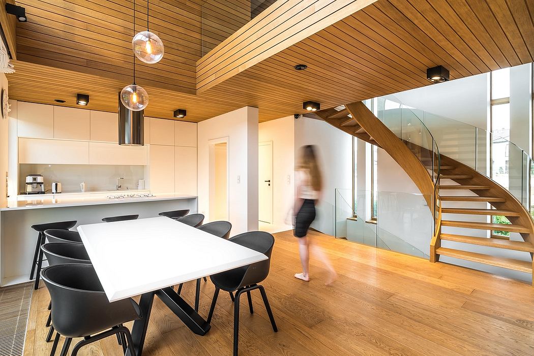 Modern open-plan kitchen and dining area with wooden ceiling, glass walls, and stairs.