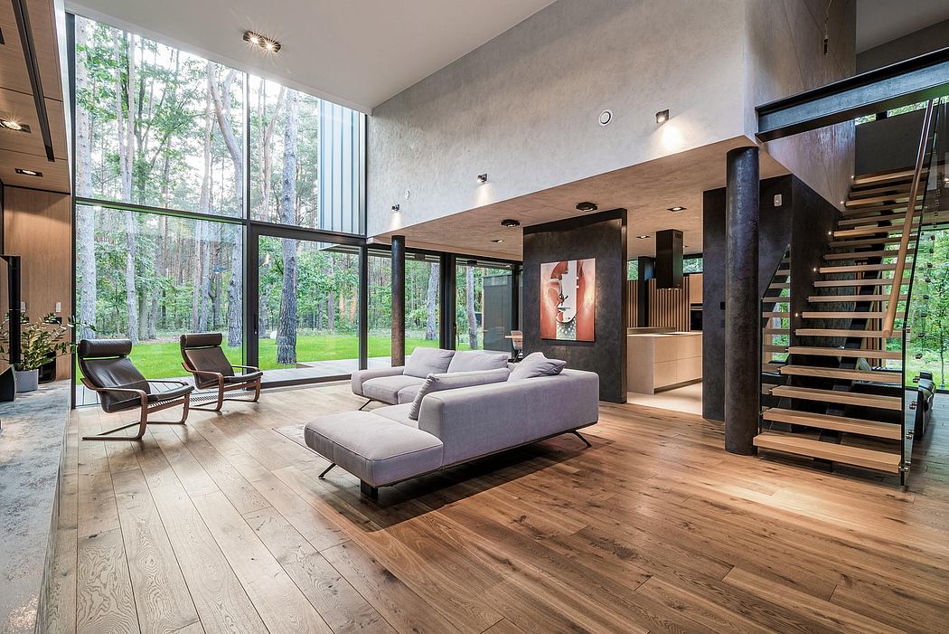 Modern, open-plan living room with floor-to-ceiling windows, gray sectional, and wood floors.