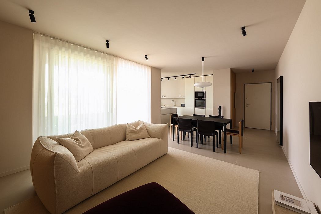 Spacious, minimalist living room with a cozy sofa, modern kitchen, and dining area.