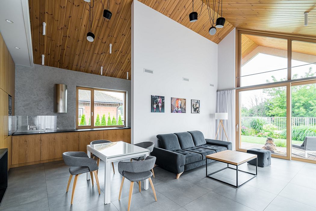 Spacious open-plan living area with wood-paneled ceiling, large windows, and minimalist decor.