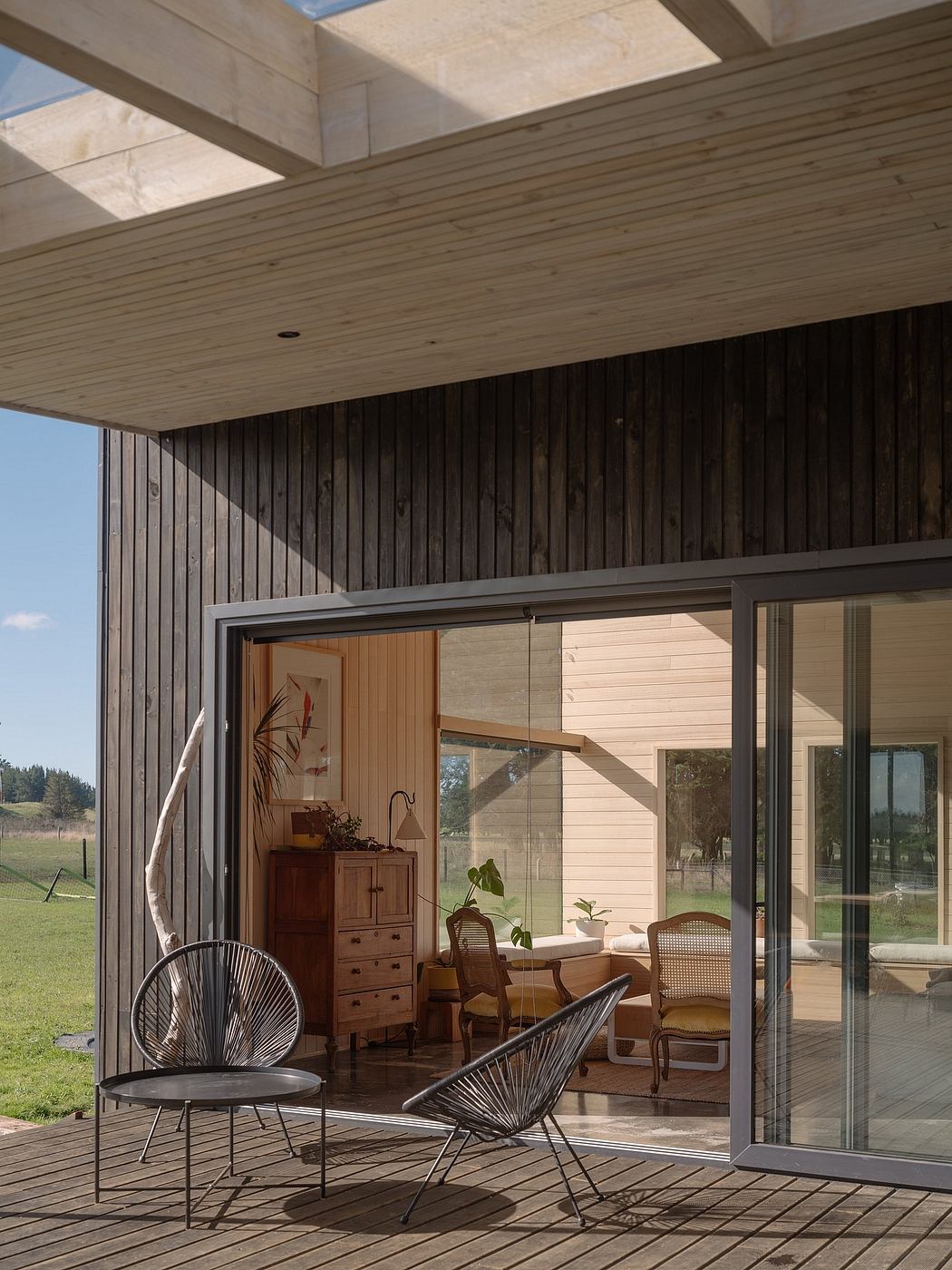 Wooden cabin with sleek modern interior, sliding glass doors, and cozy patio furnishings.