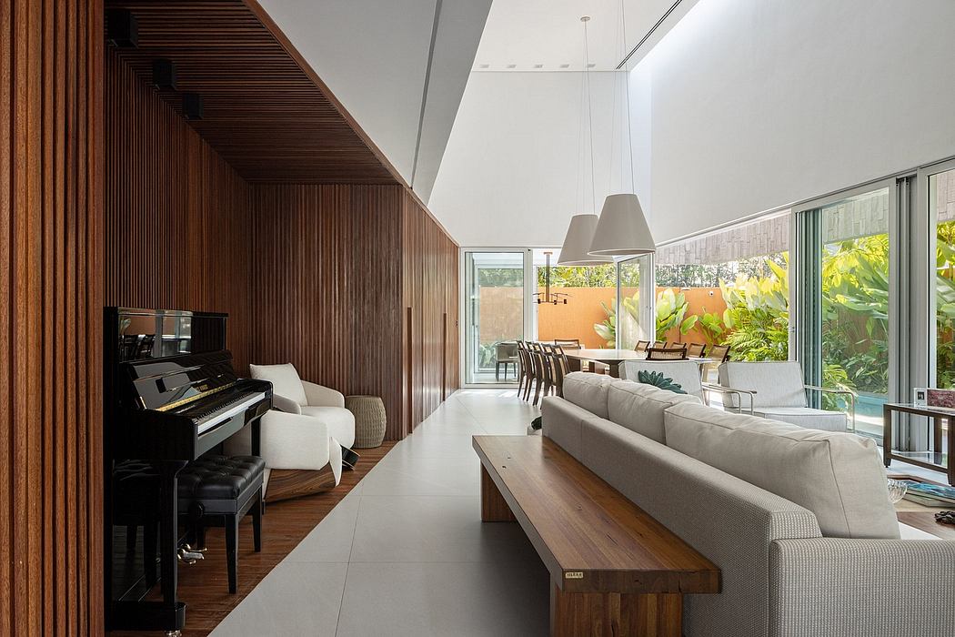 A spacious, modern living room with wooden paneled walls, large windows, and a piano.