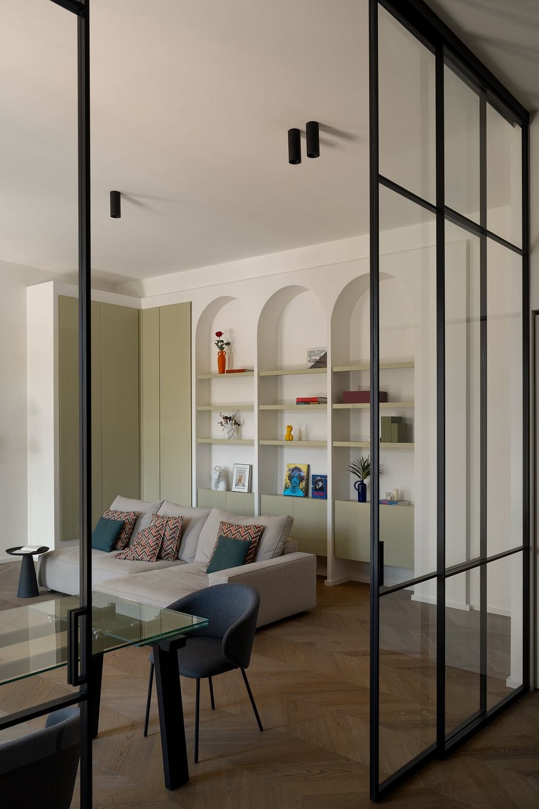 A modern living room with sleek black metal framing, shelving, and a sofa with patterned cushions.