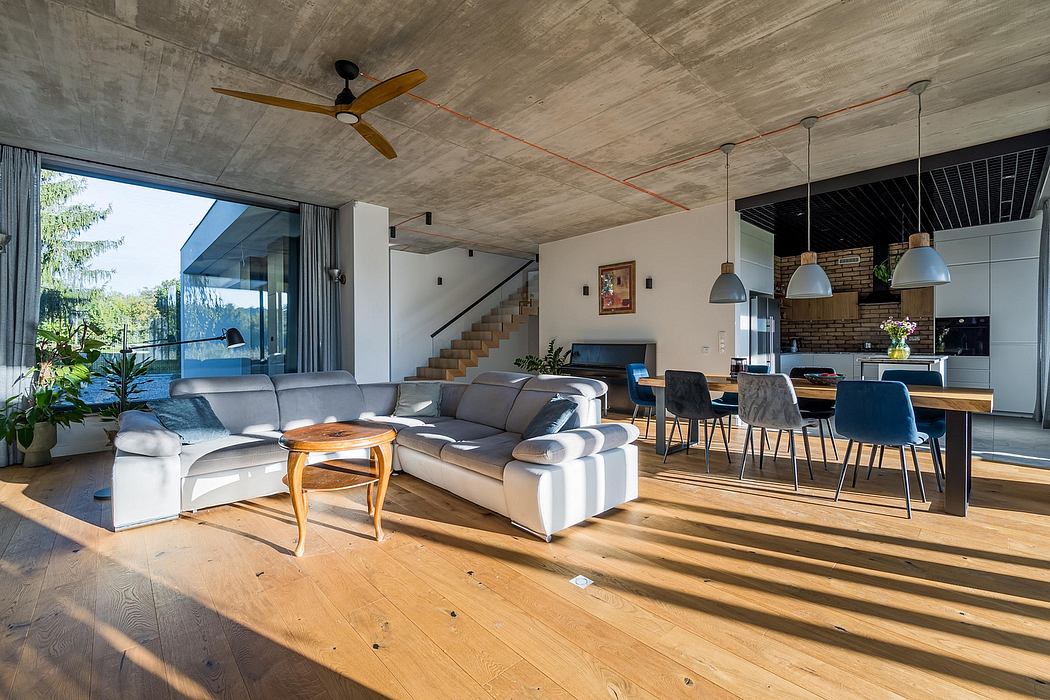 Sleek, modern living space with exposed concrete ceiling, wood floors, and large window.