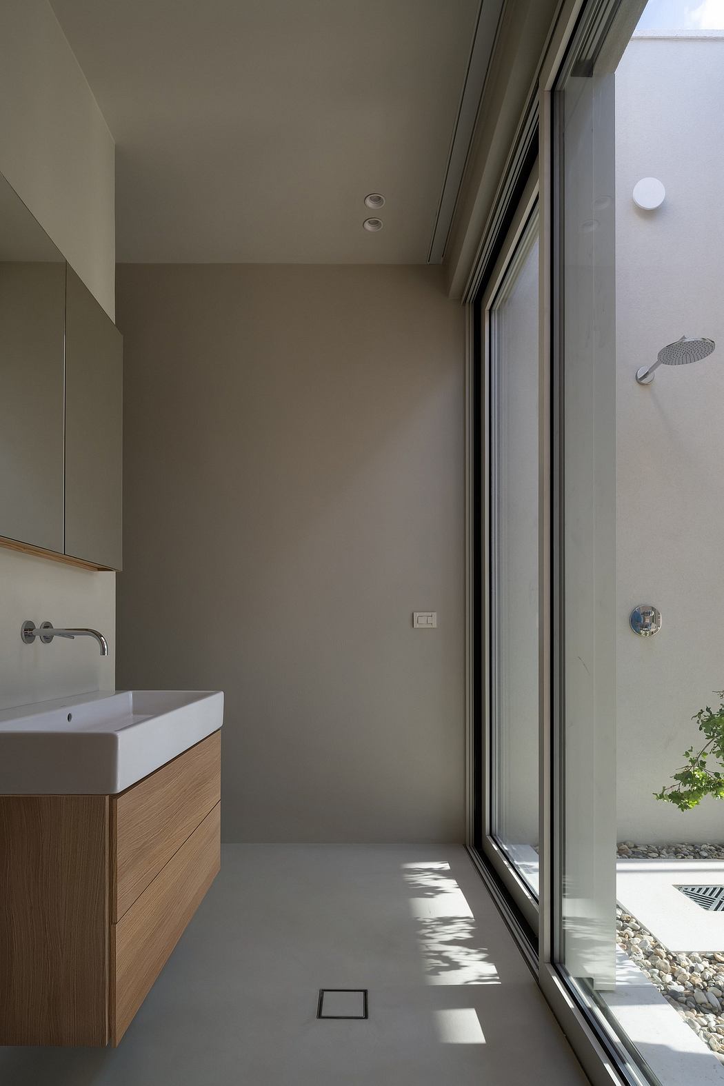 Minimalist bathroom with clean lines, large window, and wooden vanity cabinet.