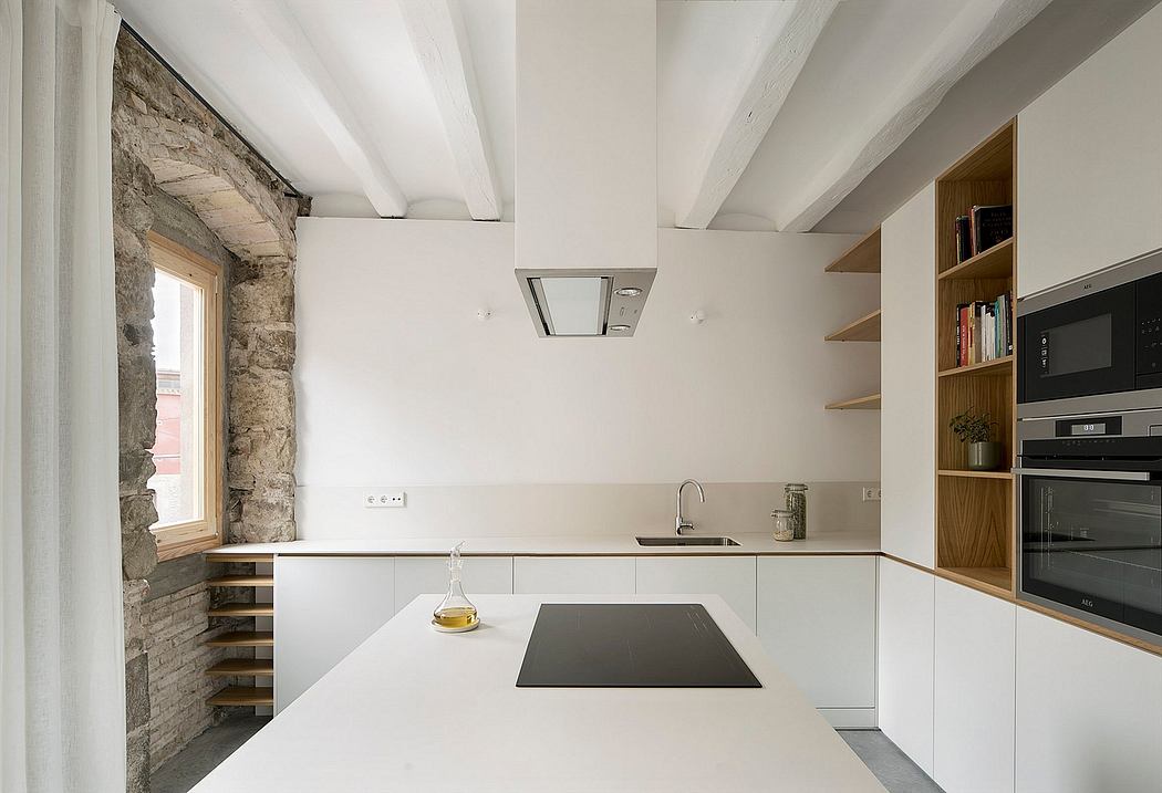 Modern kitchen with white cabinets, wooden shelves, and exposed stone wall.
