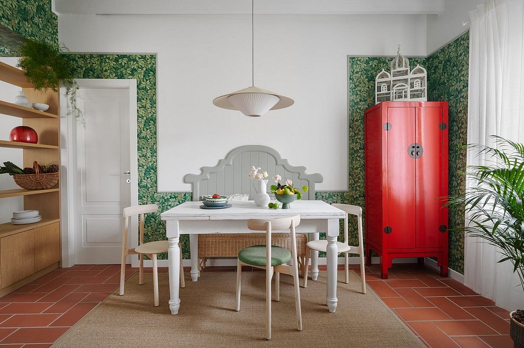 Rustic dining room with lush green wallpaper, a white table, and a vibrant red cabinet.