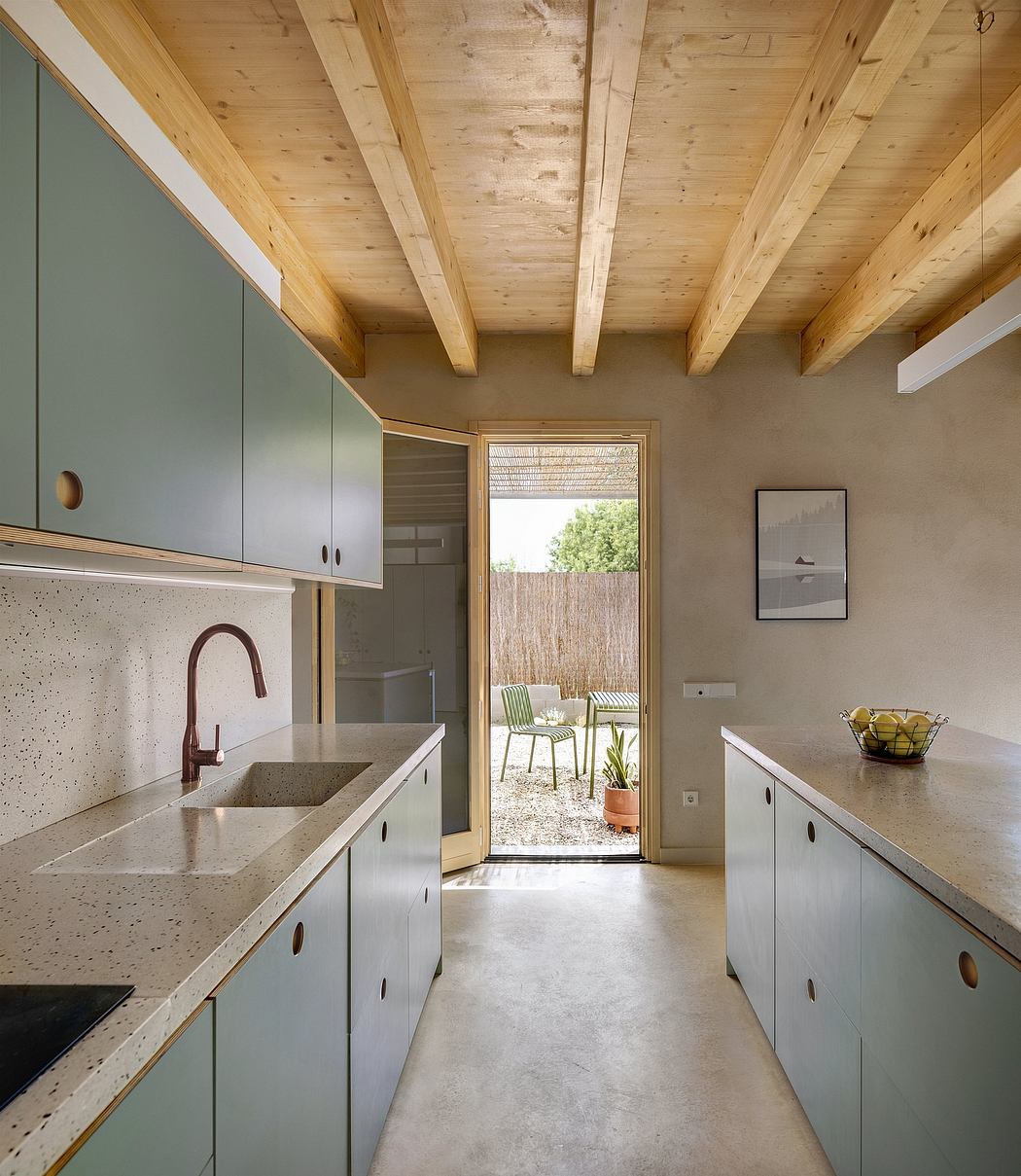 Minimalist kitchen with wooden beams, concrete countertops, and access to a small patio.