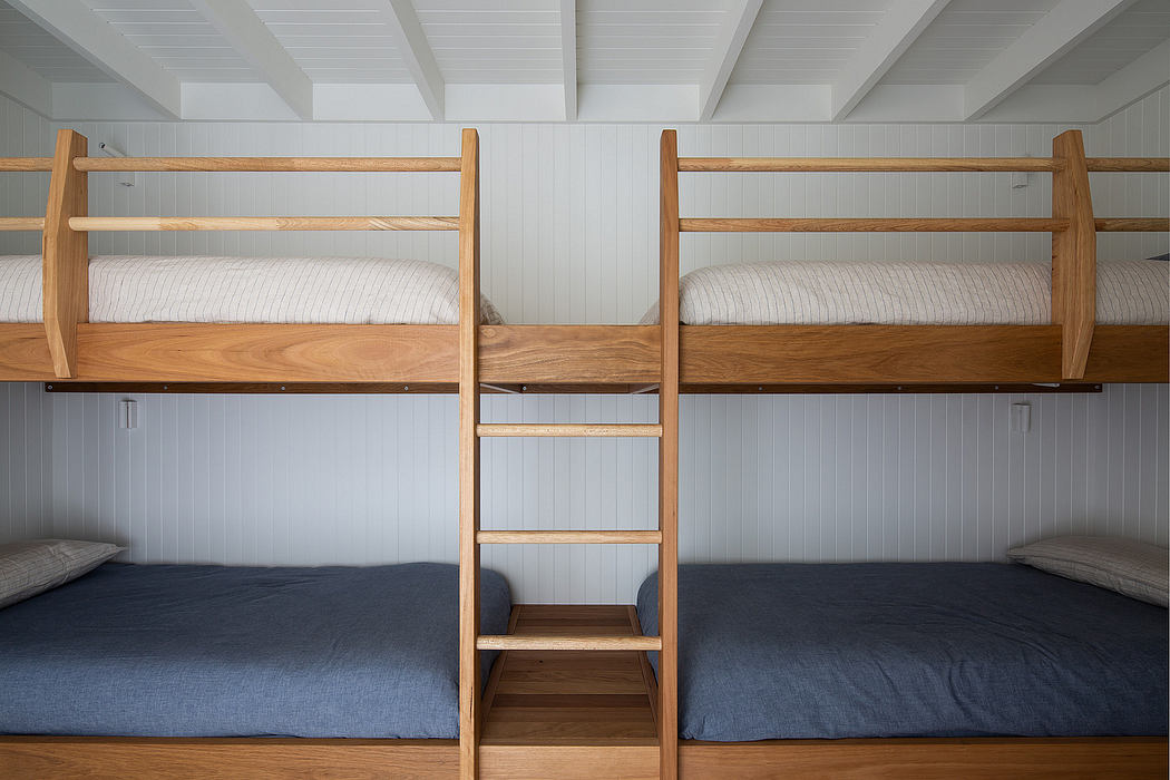 A cozy wooden bunk bed with built-in shelving in a minimalist bedroom interior.