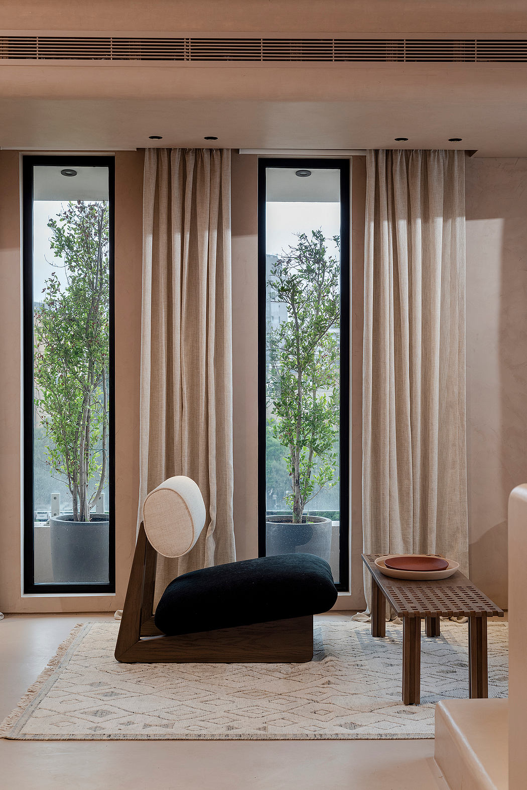 Serene living space with large windows, neutral-toned curtains, and minimalist furnishings.