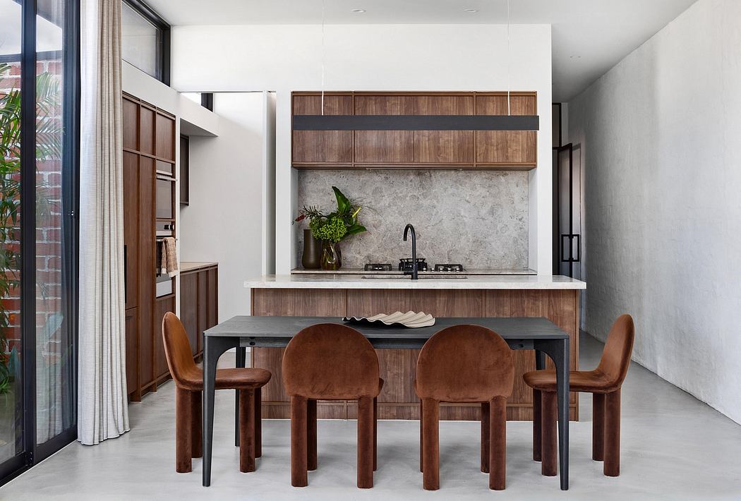 Modern kitchen with wooden cabinetry, marble backsplash, and minimalist dining furniture.