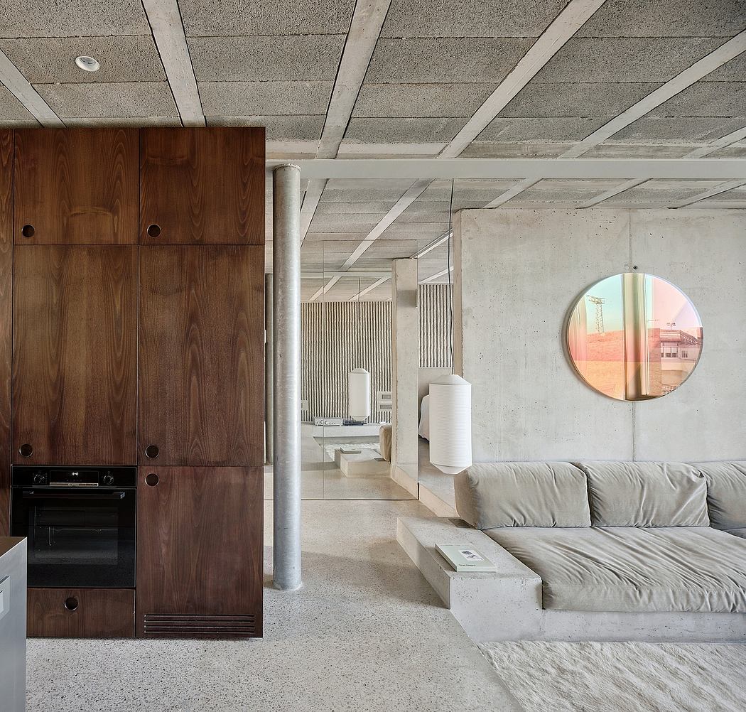 Minimalist living room with textured concrete walls, wooden cabinetry, and round mirror.